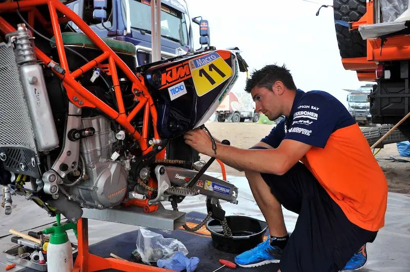 Benji Melot en train de faire de la mécanique sur le Dakar quand il faisait partie de la team KTM