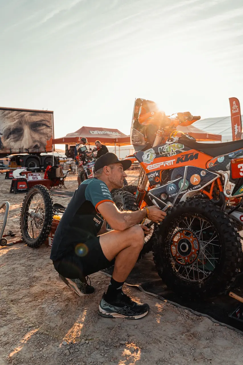 Benji Melot fait de la mécanique sur sa moto lors du Dakar